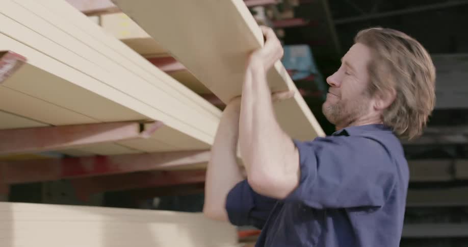 A man is choosing lumber from a pile
