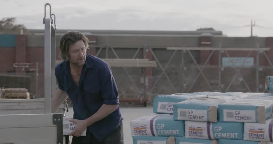 Man unloads bags of concrete from a truck