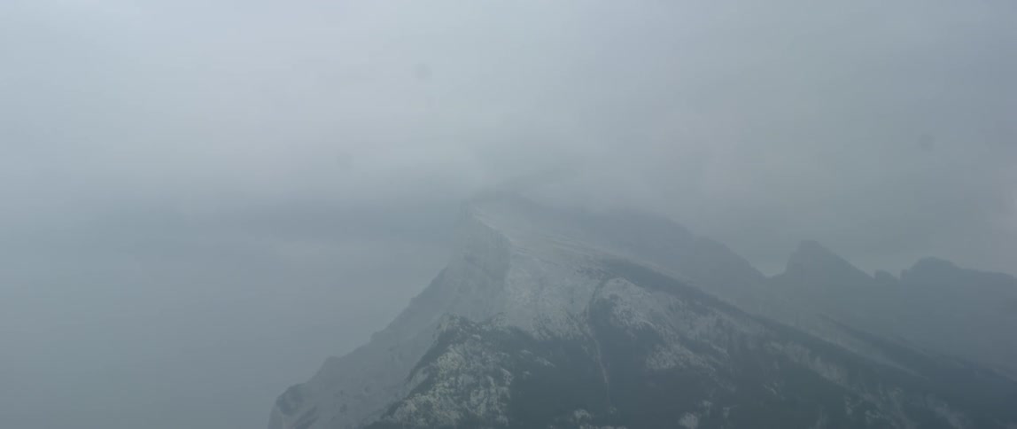 Clouds float over a snowy mountain peak