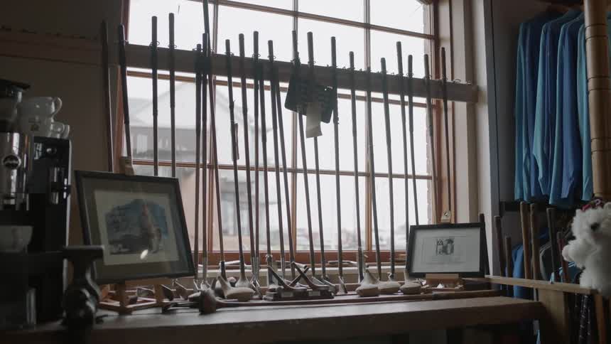 Golf clubs stand on a table next to a window