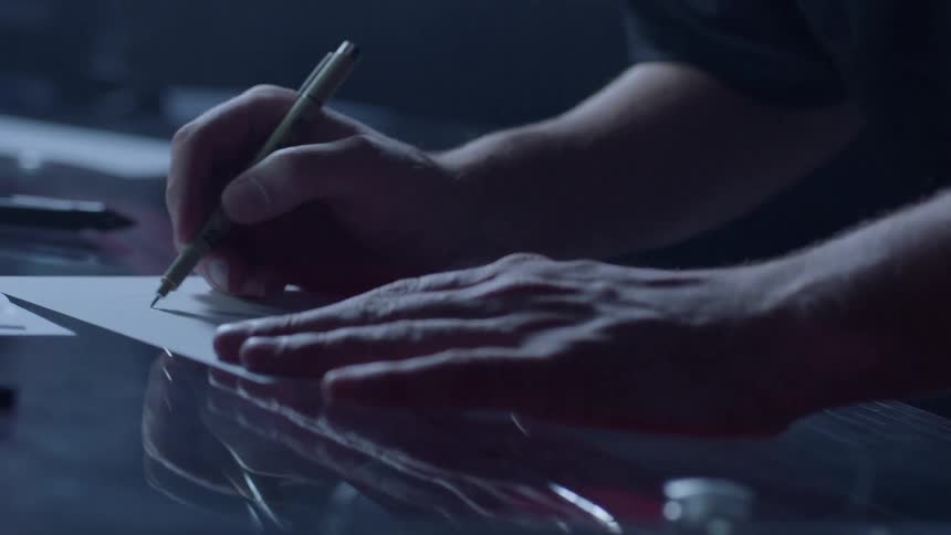 A man uses a pen to write on a piece of paper