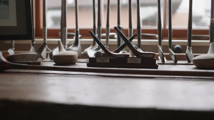 Golf clubs and pieces sitting on a table near a window in a city