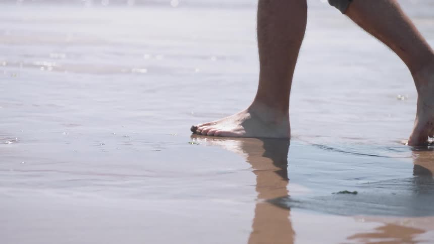 A man walks on the wet sand