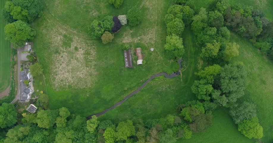 A stream is flowing past a rural home during the day