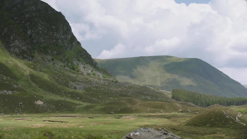 The valley ahead has mountains covered with green