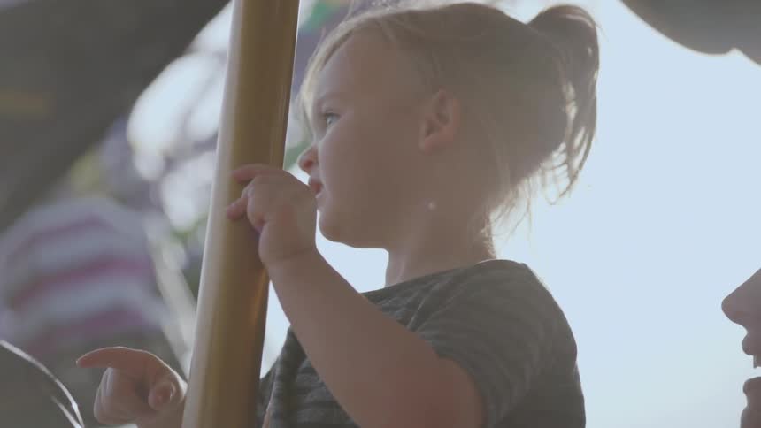 Woman and child ride on a merry go round on a sunny day