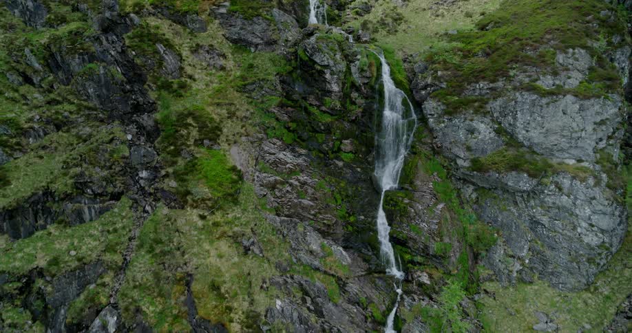 A waterfall flows over a rocky mountainside