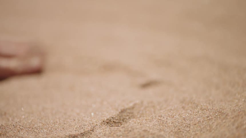 A man rubs his hand over sand