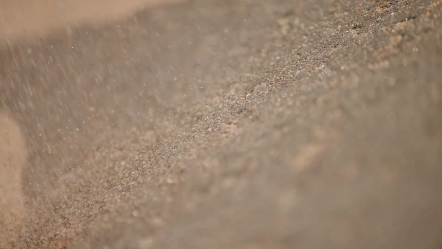 Grains of sand fall and shift in daylight