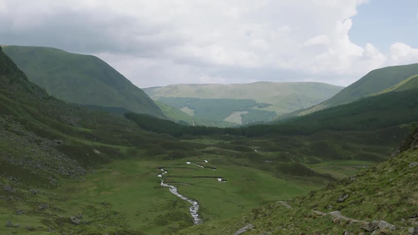 A river is flowing through a mountain valley on a cloudy day