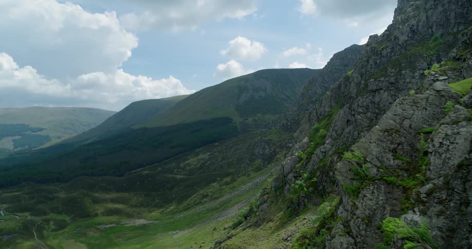 The mountain is covered with green and falls into a valley of grass