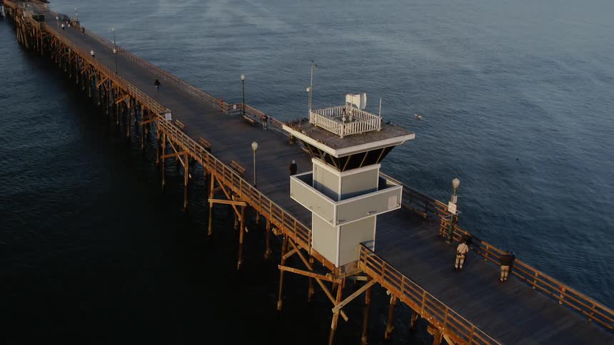 People walk on an ocean pier at sunset
