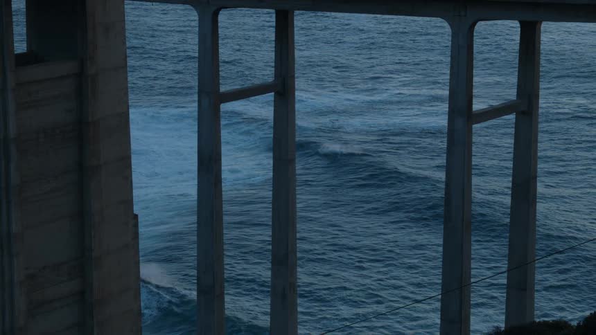 Waves rolling under a bridge