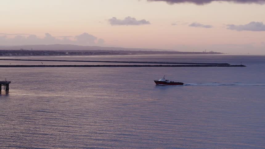 A boat is sailing towards a pier at dusk