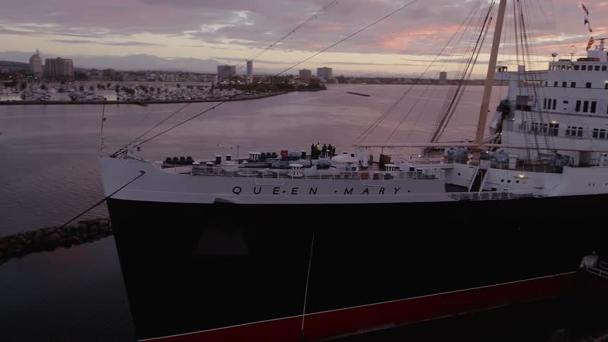 A ship floats in a port at sunset
