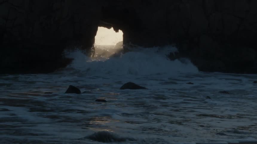 Waves crash through eroded rock opening
