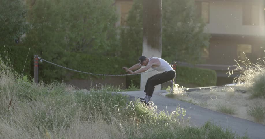 Man does a jump over a chain blocking a trail
