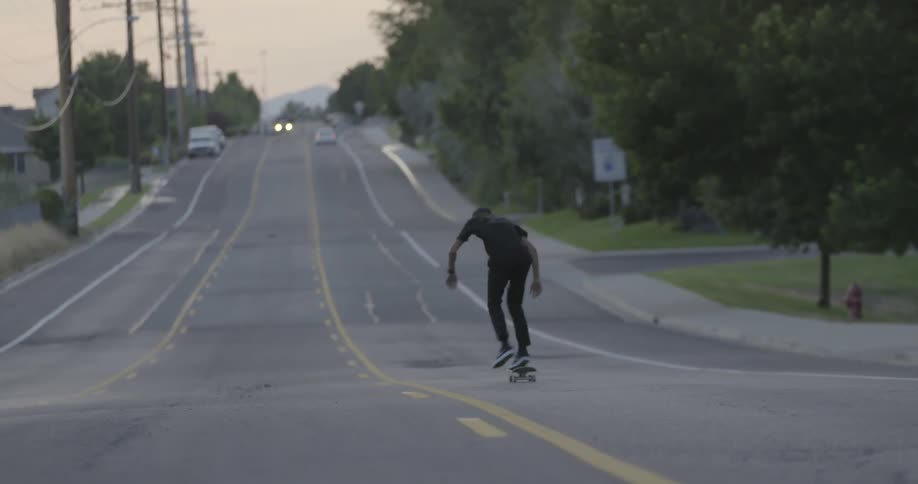 Man riding his skateboard downhill on a street