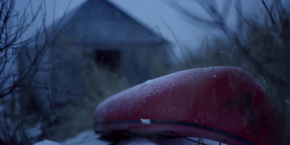 Snow is falling on a red kayak