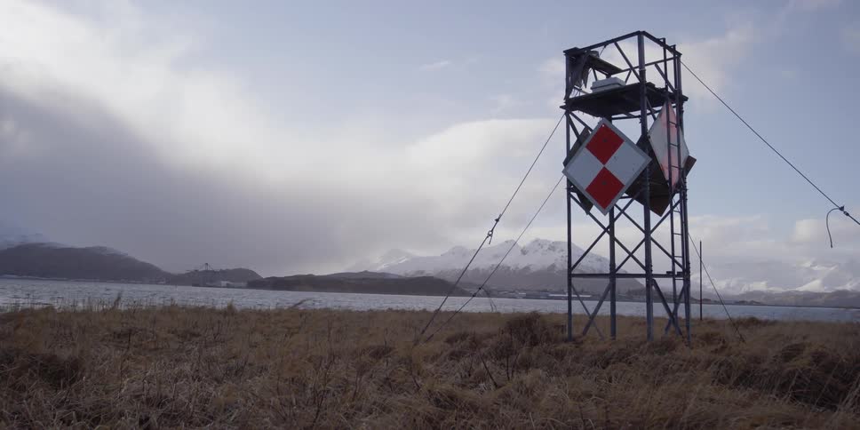A tower stands next to a mountain lake