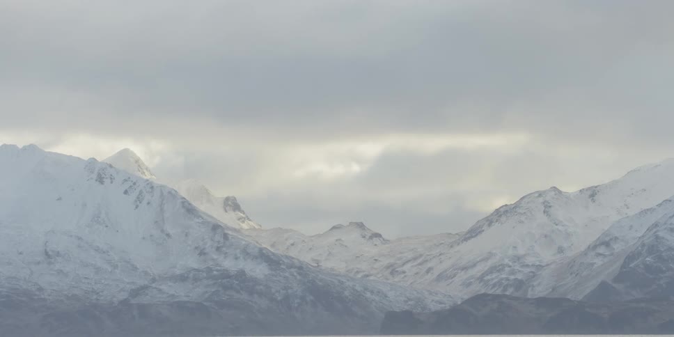 Clouds passing over snowy mountains