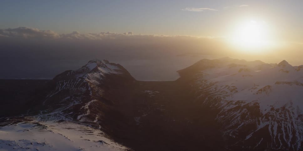 The sun sets over snowy mountains