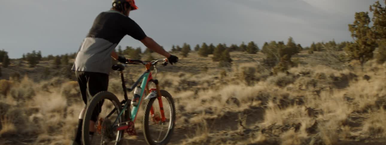 Man pushes a bicycle up a rural hillside