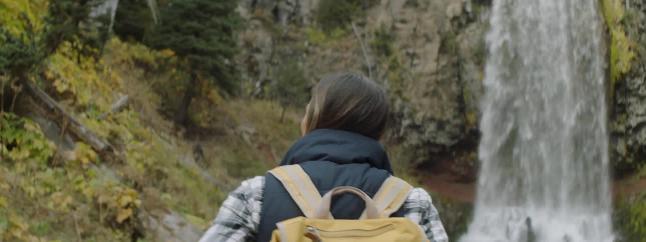 A hiker stops to look at a waterfall