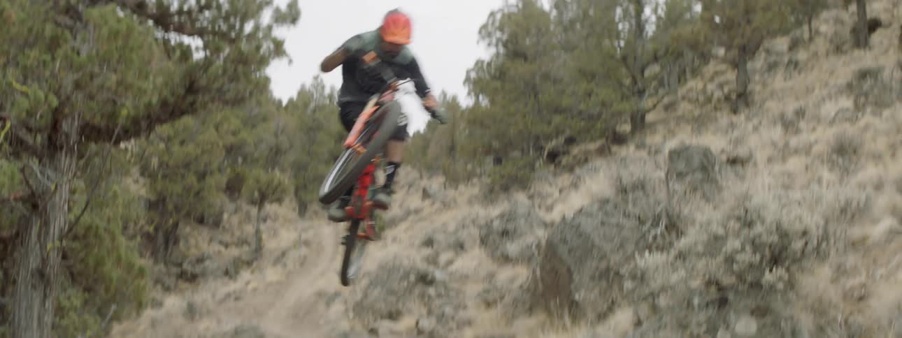 A bicyclist goes over a jump on a mountainside