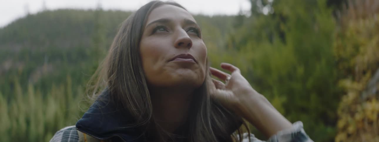 A woman looks around by the trees
