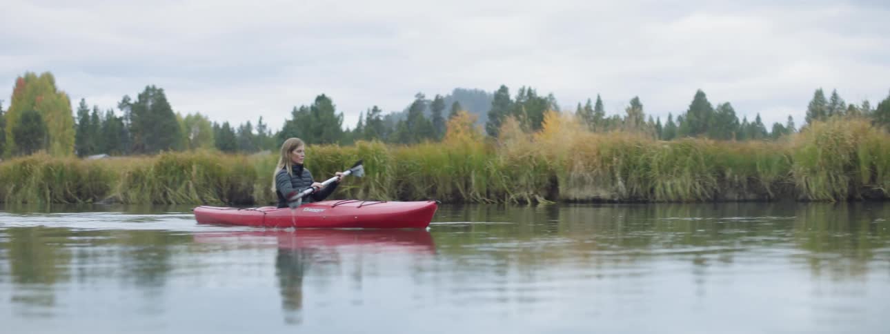 A woman kayaks on a river