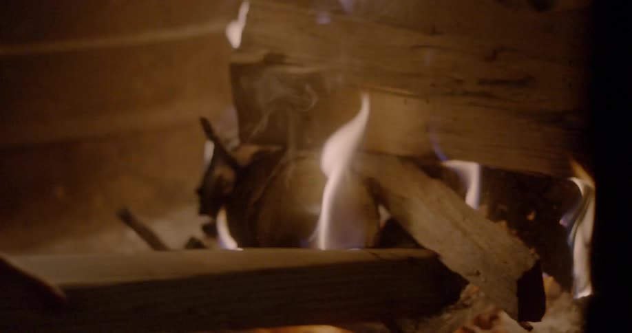 A man stokes a fire in a fireplace
