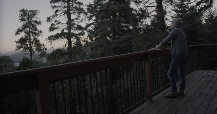 Man stands on a balcony in mountains at sunrise