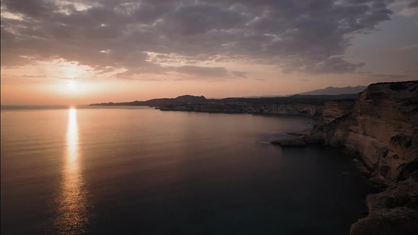Sun shines and sets by limestone cliffs in the sea