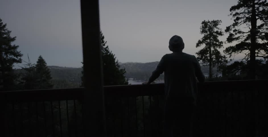 A man stands on a cabin balcony