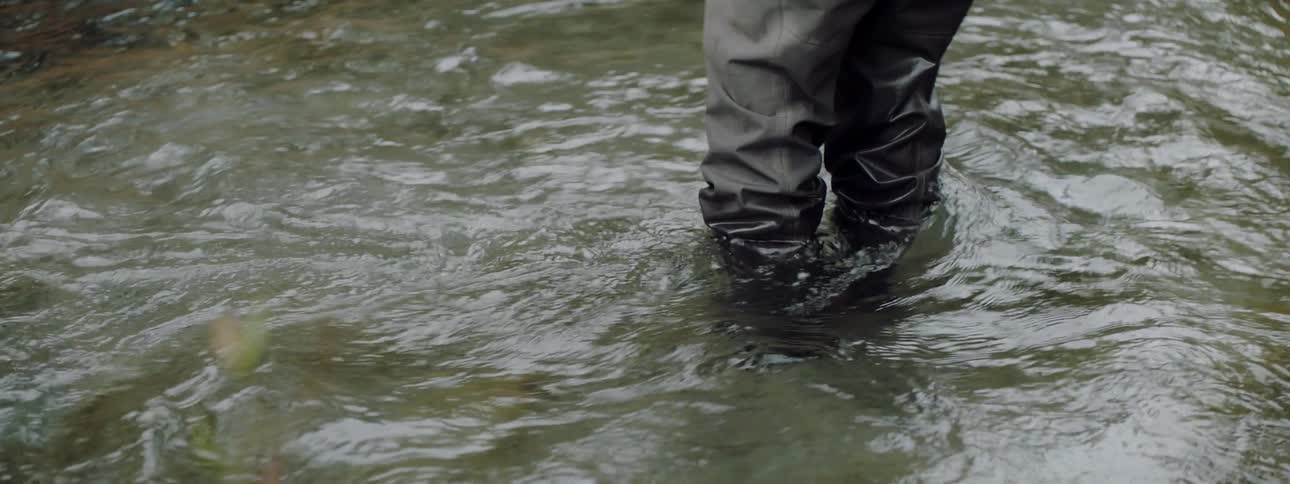 River water flows around a fisherman's legs
