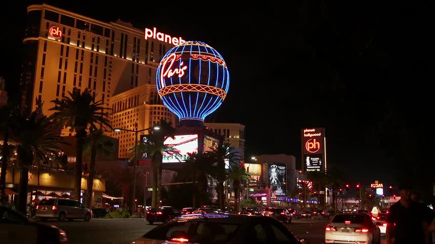 Cars drive down a street near several lit up hotels at night