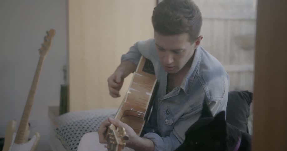 Man pets a dog and plays guitar