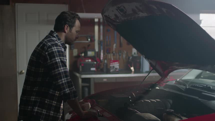 A man looks at the engine of a car in a garage