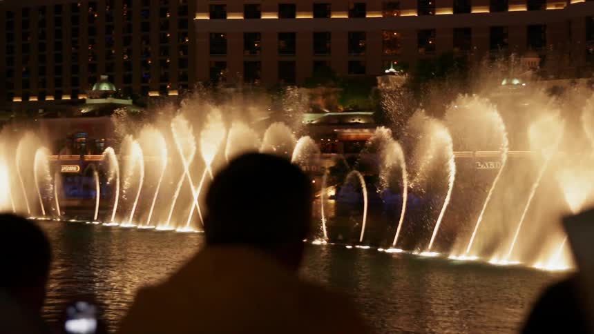 A person is using their phone to record the spraying fountains