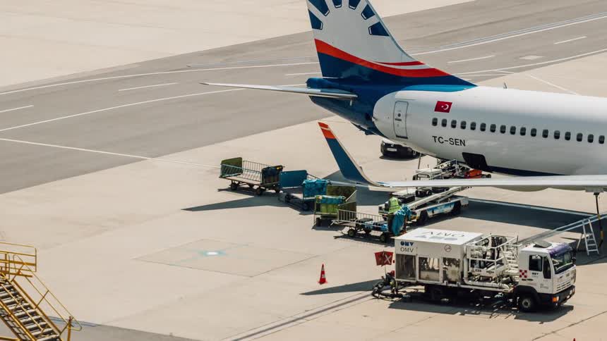 Luggage carrier pulls up to an airplane at an airport