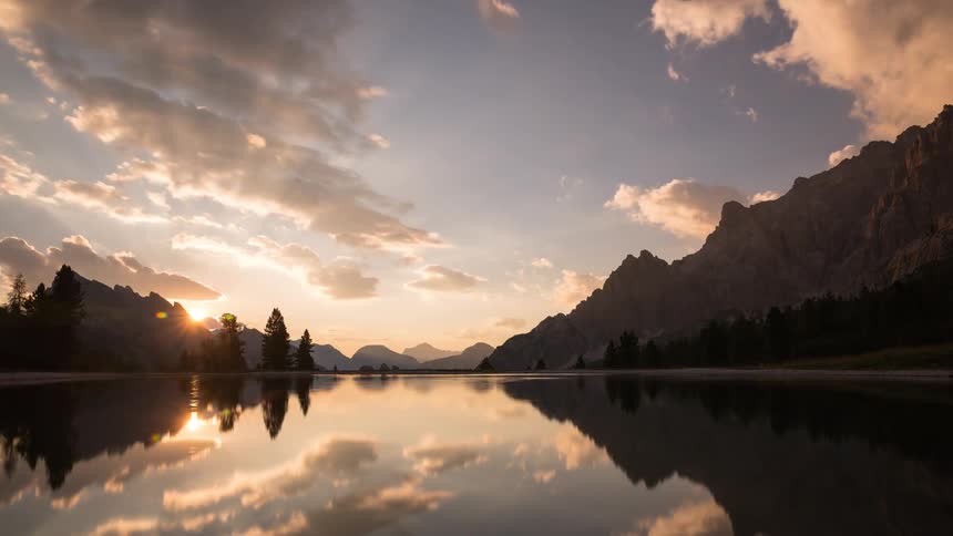 The water of the mountain lake is reflective at sunset
