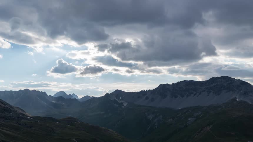 Clouds move over mountain peaks on a sunny day