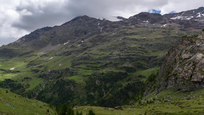 Clouds roll over a grassy mountain