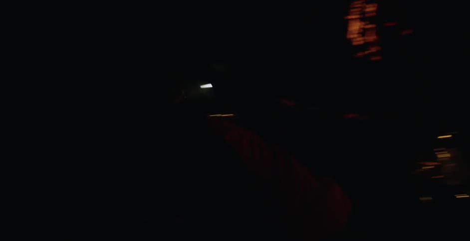A man rides a bicycle from a garage at night