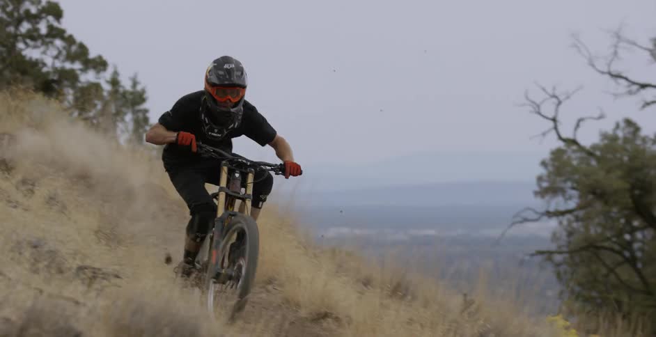 A man is riding a mountain bike on a dirt trail at dusk