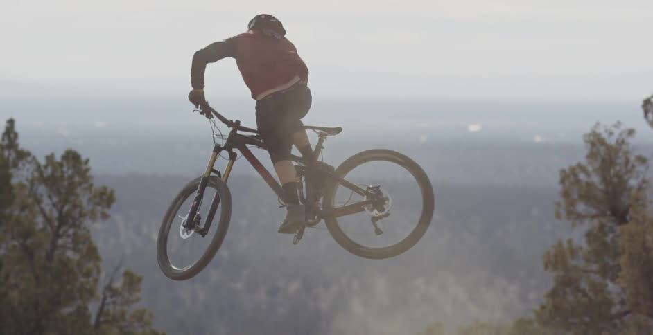 A man turns the bike as he jumps over the dirt hill