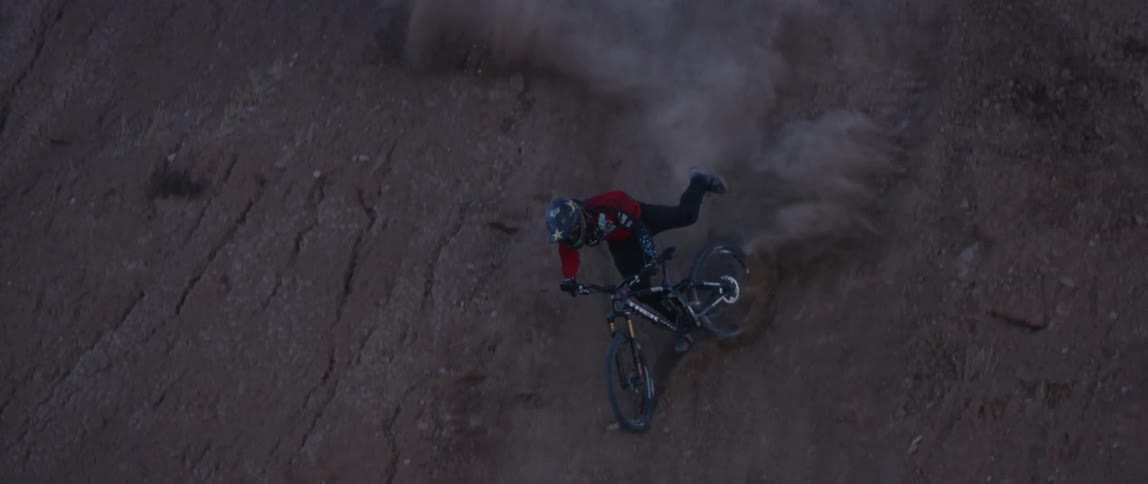 A bicyclist falls after doing a trick on a mountainside