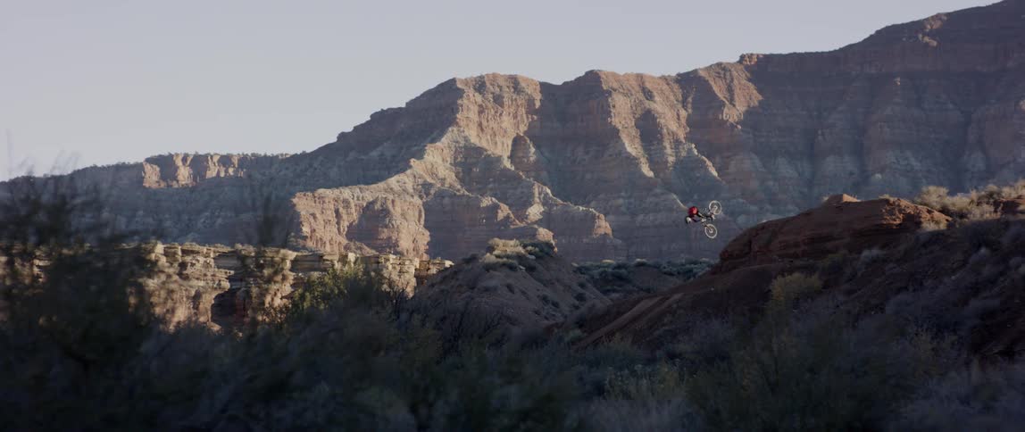 A person does a flip off a mountain on a bicycle