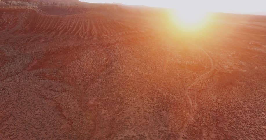 The sun shines on the dirt and plant covered landscape